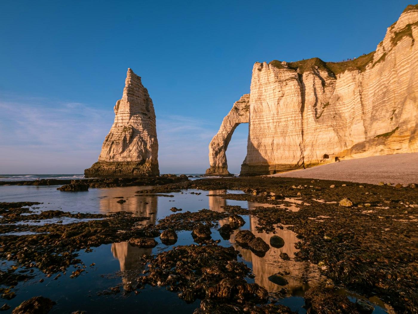 White cliffs, a natural arch, and sea stack at sunset