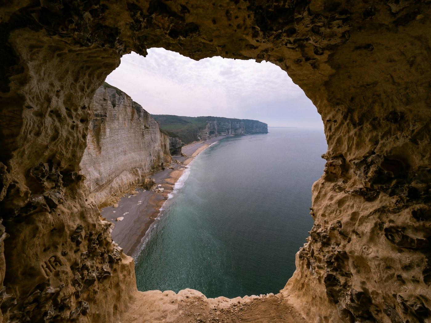 Coastal cliffs and beach viewed through a natural cave opening