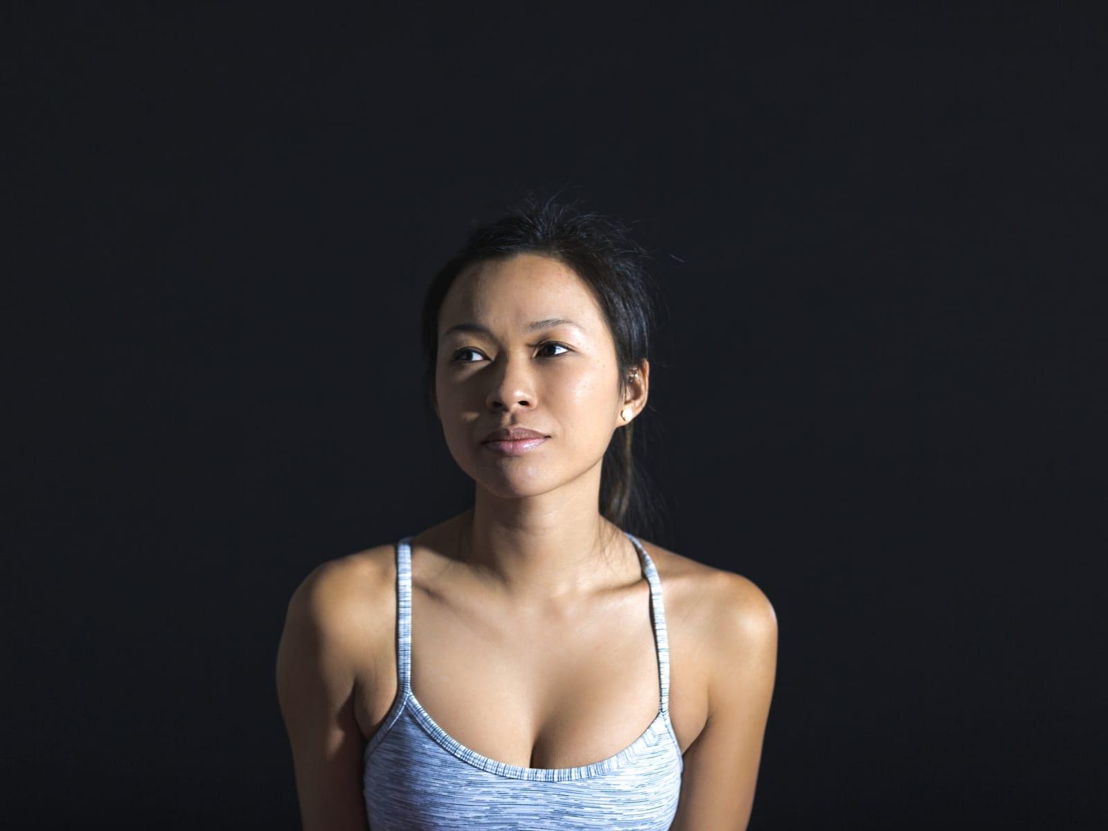 Two people in plain mid-tone clothing photographed against pale stone